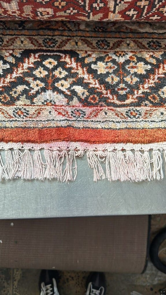 Image showing a rug with dye bleed on its fringe placed on a metal surface.