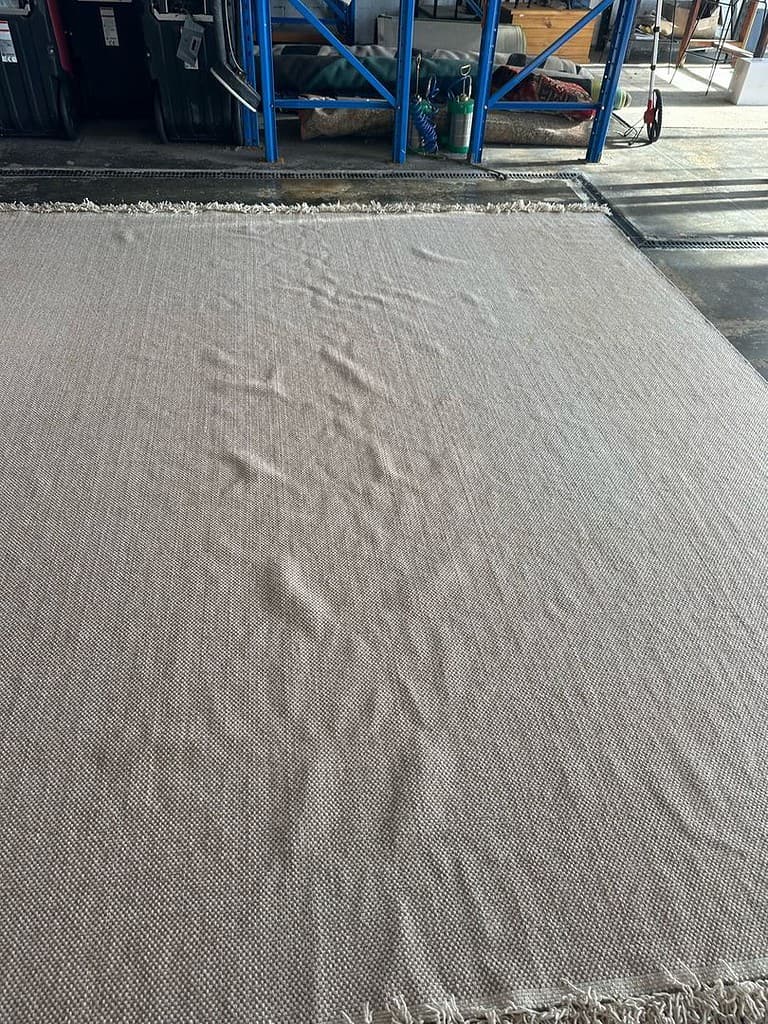 Handmade Wool Rug in Industrial Workspace Flat handmade wool rug with wave pattern in a warehouse setting.