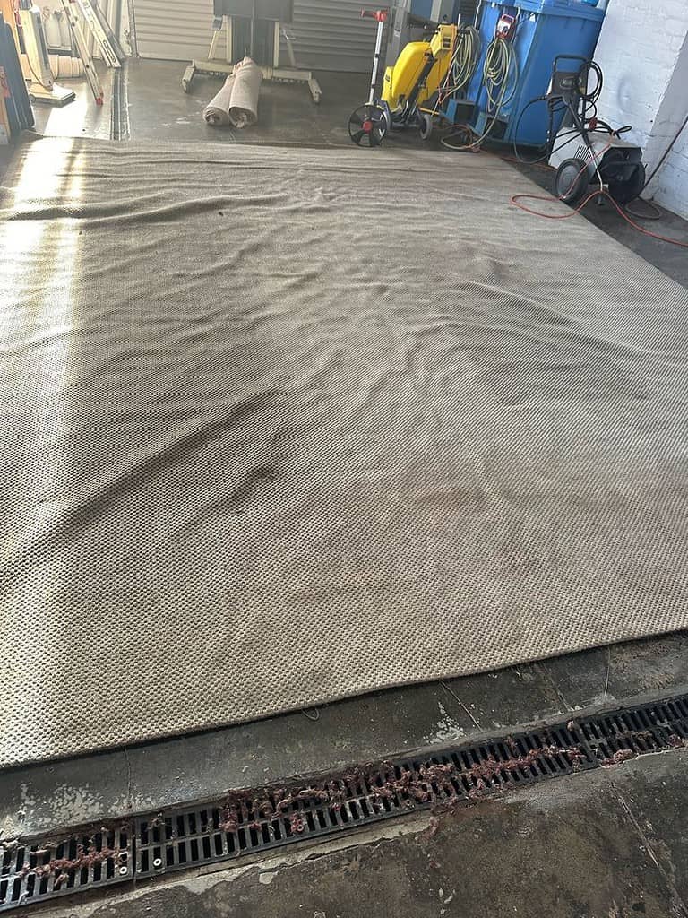 Jute rug on concrete floor with cleaning equipment in an industrial setting.