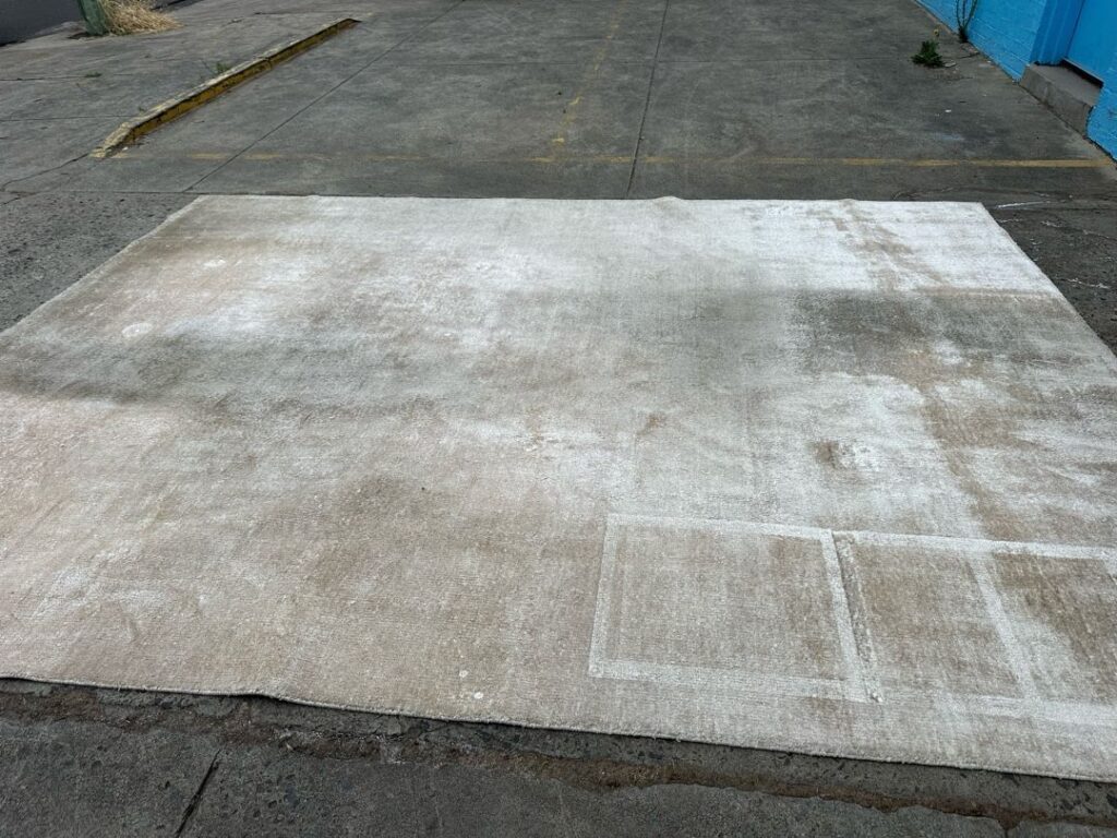 Large rug on concrete surface with visible marks and sections.