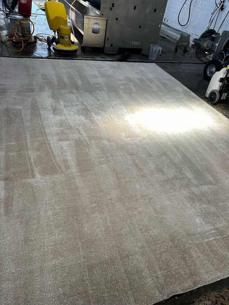 Image of a large rug in a professional cleaning facility with industrial equipment.