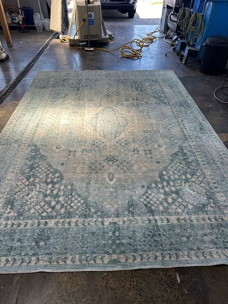 Rug with intricate patterns on a concrete floor in an industrial workshop.