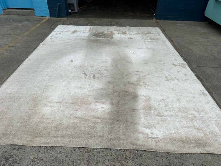 Stained rug on concrete floor in industrial setting.