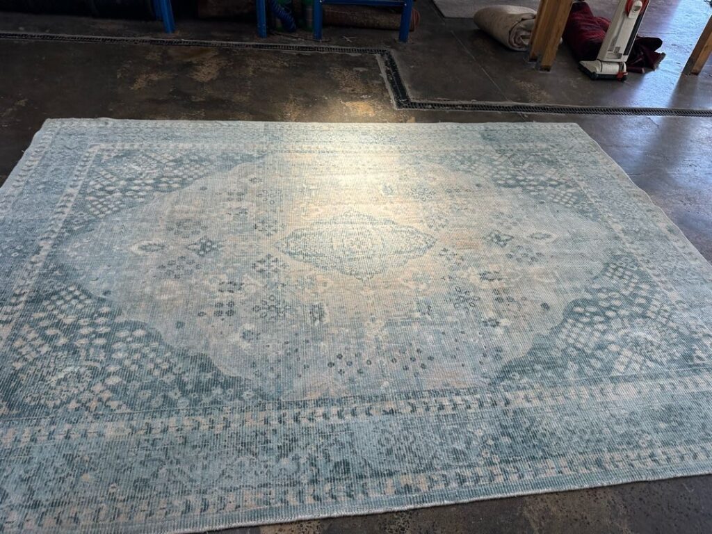 Image of a large blue and white patterned rug on a concrete floor in an industrial setting.