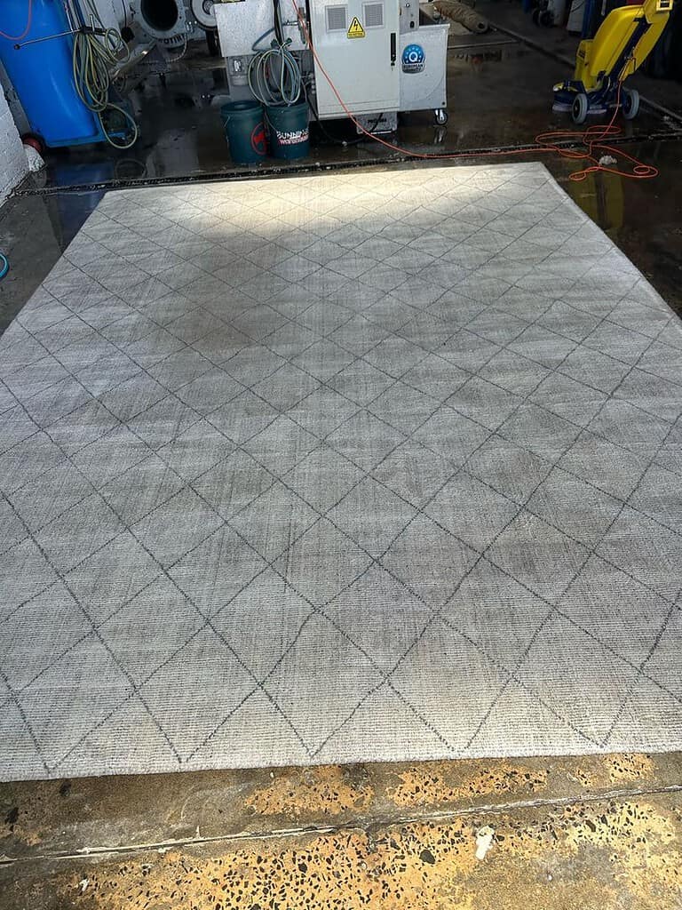 Rug with diamond pattern in an industrial setting with cleaning equipment.