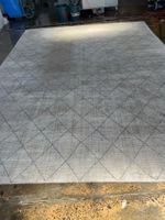 Rug with diamond pattern in an industrial setting with cleaning equipment.