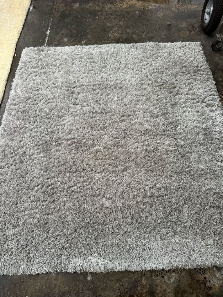 Light gray shaggy carpet on concrete floor in industrial setting.