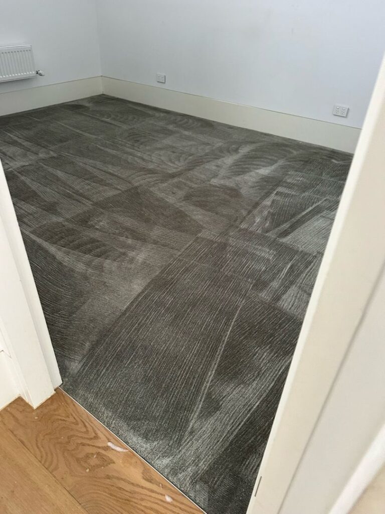 Room with freshly cleaned shiny nylon plush carpet and white walls.