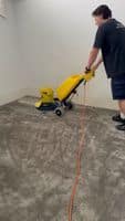 Person using yellow carpet cleaning machine on grey plush carpet.