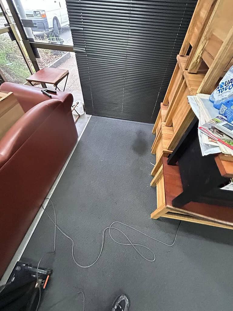 Image of a stained carpet in an office with furniture and a window.