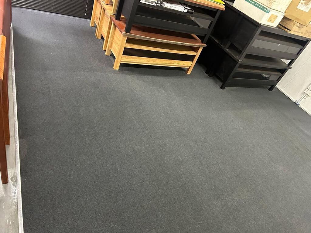 Clean carpet with wooden benches and shelving units in a factory office.