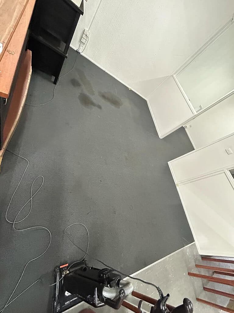 Image of a stained office carpet with cleaning equipment in view.