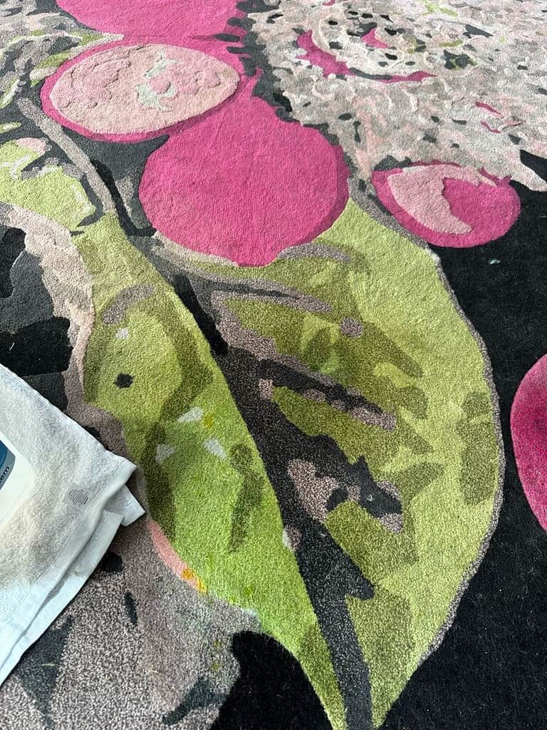 Vibrant Floral Carpet Close-Up Close-up of a colorful floral-patterned carpet with a white cloth on the side.